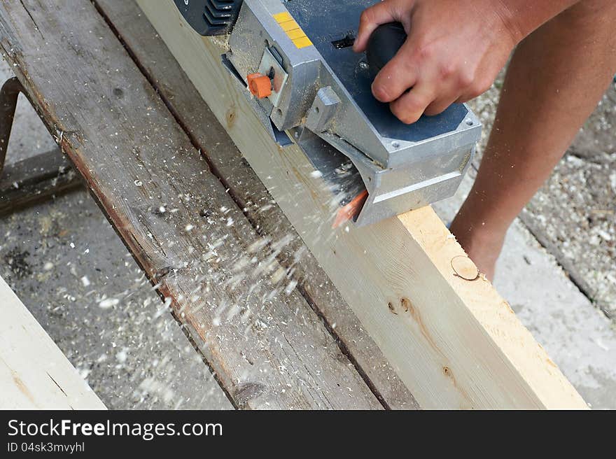 Carpenter with electric plane outdoors