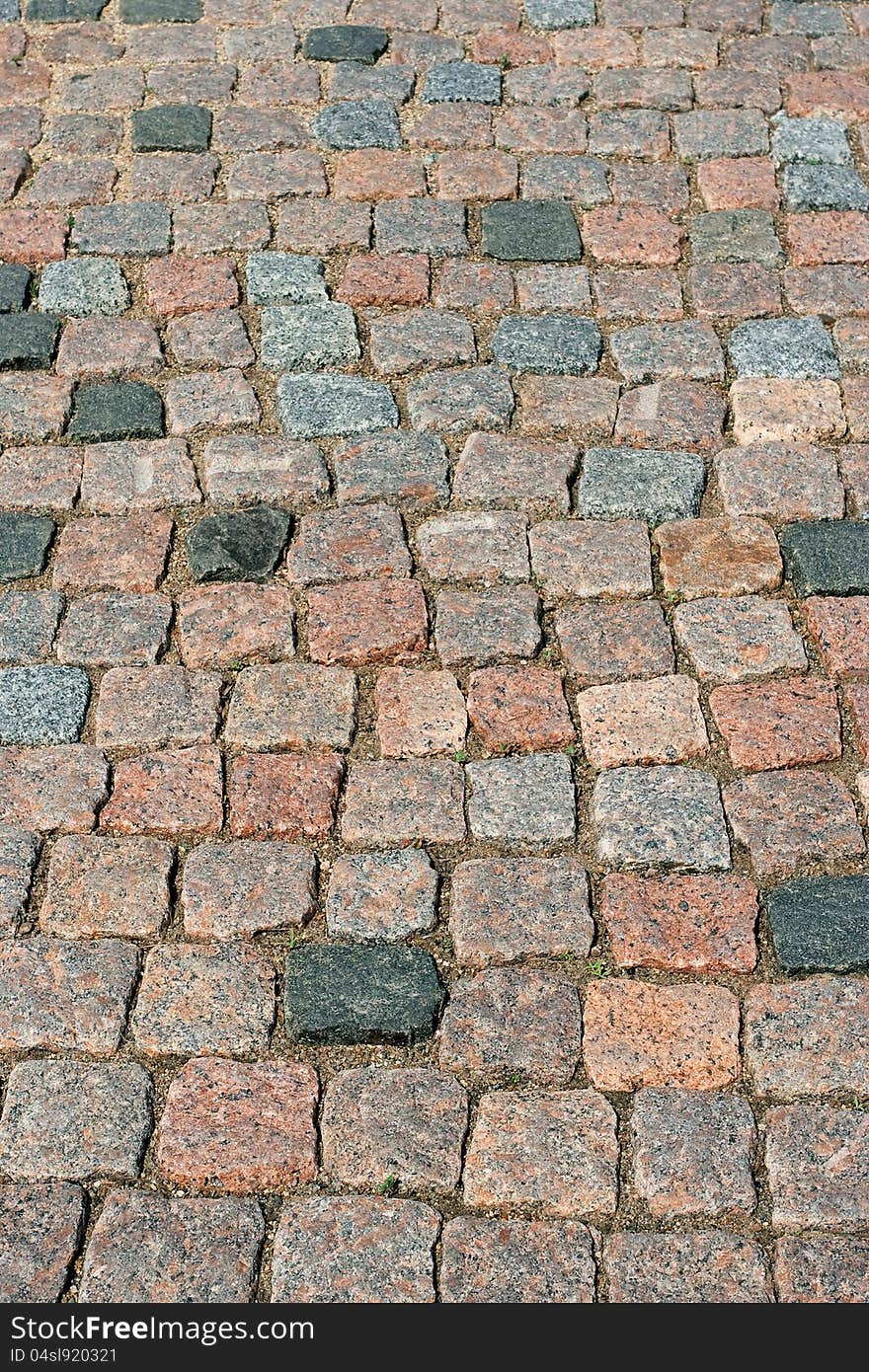 A fragment of the pavement made of granite stone. Background, texture. A fragment of the pavement made of granite stone. Background, texture