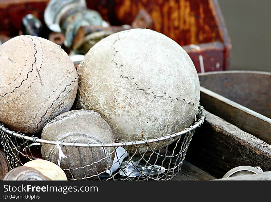 Vintage baseballs, and softballs in a wire basket.