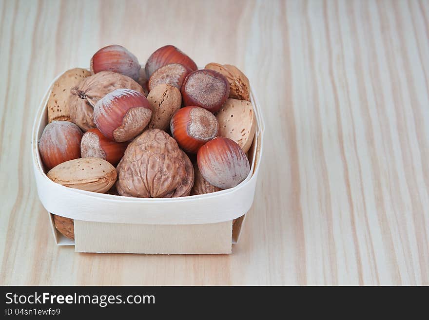 Basket with wood, walnuts and almonds. On a wooden texture.