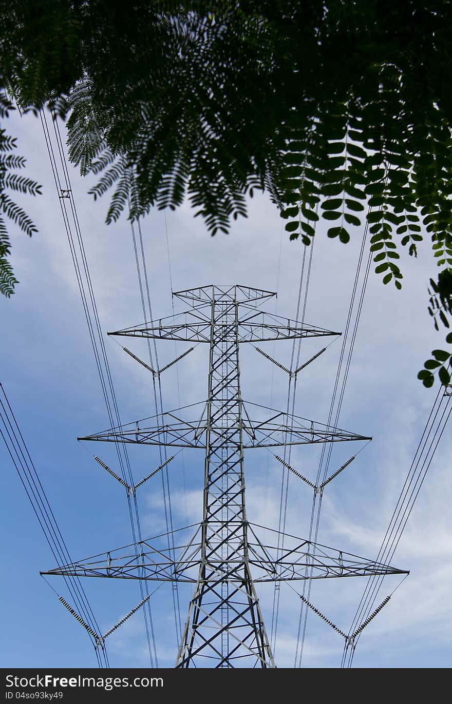 High voltage electricity pylon under the rear of the leaves in the midst of the clouds the sky. High voltage electricity pylon under the rear of the leaves in the midst of the clouds the sky.