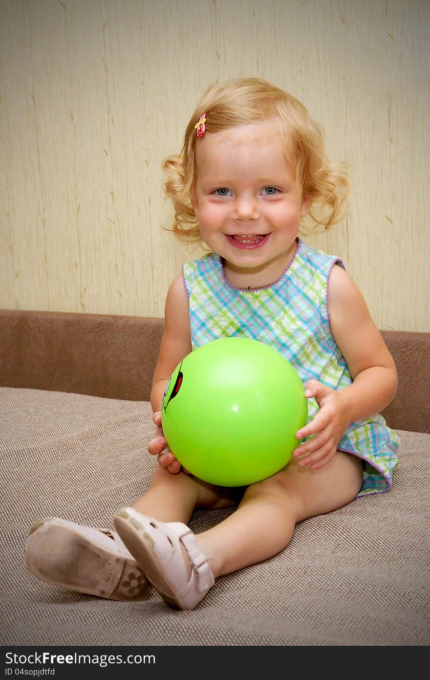 The little blond smiling baby girl with ball