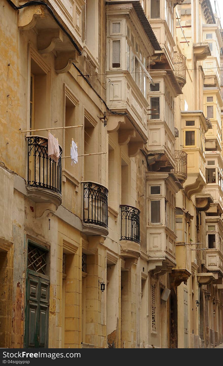 Sandstone streets and Maltese box balcony windows overlook the narrow streets of Valetta, Malta. Sandstone streets and Maltese box balcony windows overlook the narrow streets of Valetta, Malta.