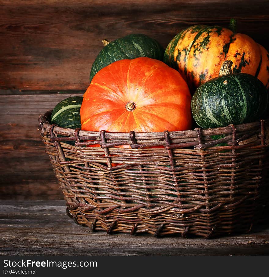 Harvested pumpkins in  basket  over wooden surface