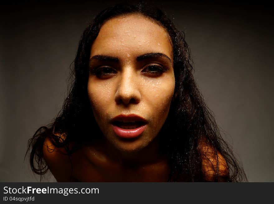 Portrait of a girl on a dark background. Water on her face.