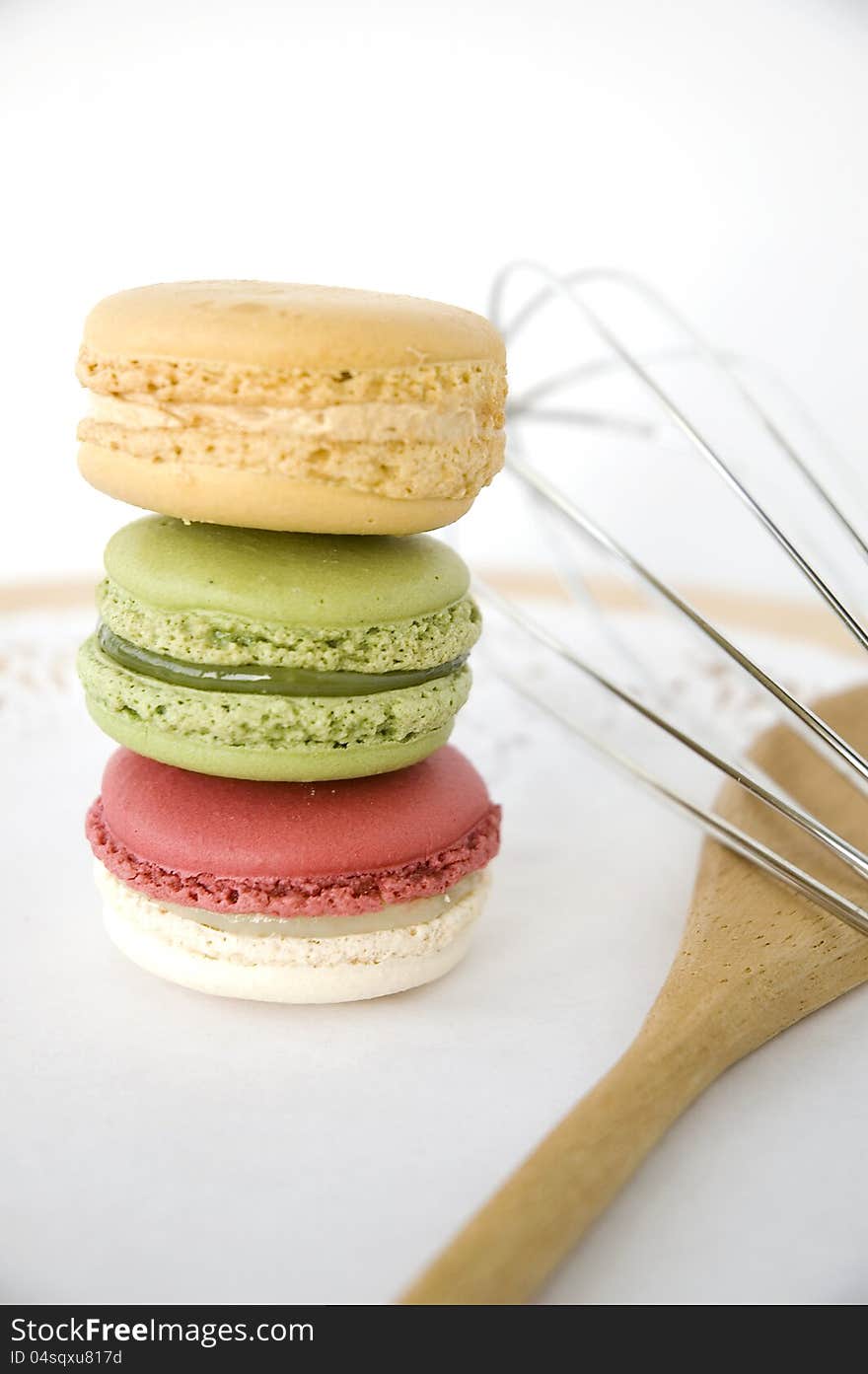 Stack of macarons with kitchenware on white background