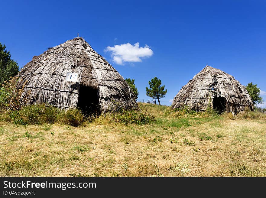 Two traditional straw huts in greek country, on a sunny day