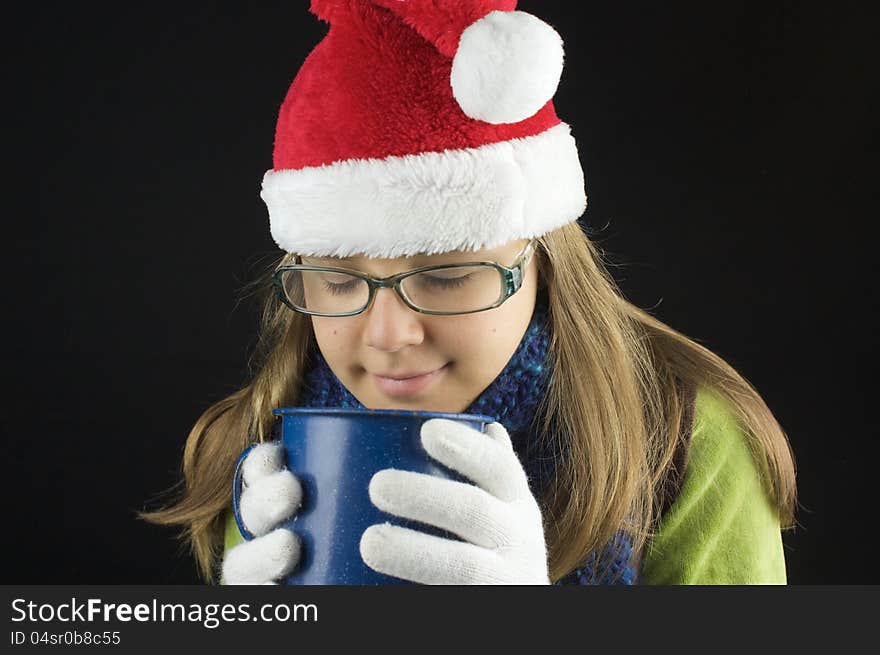 Young girl wearing winter clothing holding cup with black background