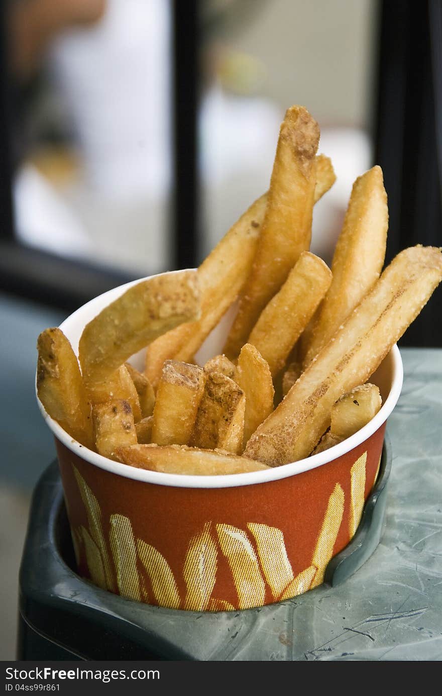 A cup of French Fries waits to be eaten at a baseball game. A cup of French Fries waits to be eaten at a baseball game.