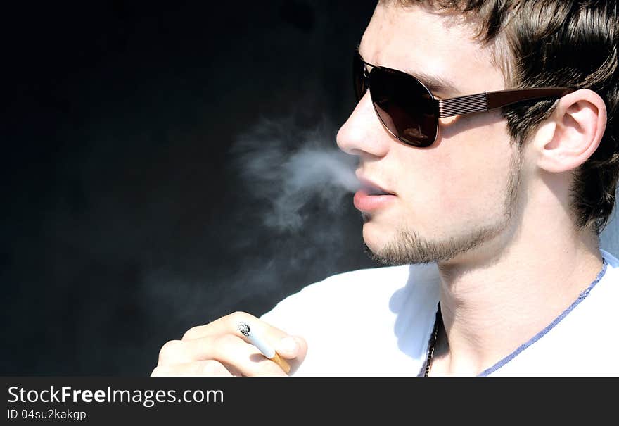 Stylish guy in sunglasses smoking a cigarette. Stylish guy in sunglasses smoking a cigarette