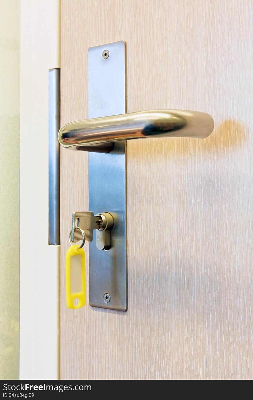 Key in the lock of the office door with yellow name tag. Key in the lock of the office door with yellow name tag