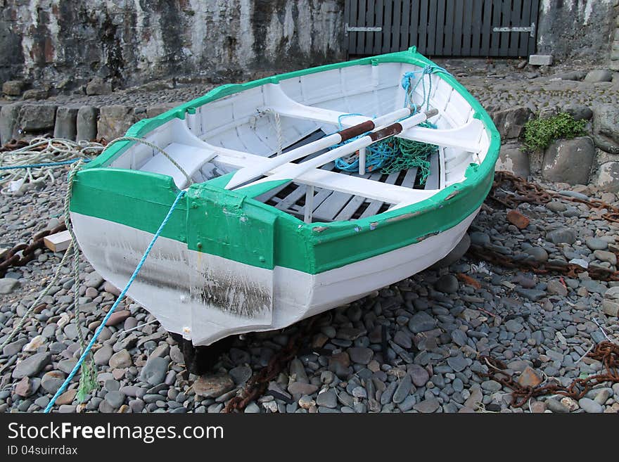 A Moored Rowing Boat on a Dry Stony Harbour Floor. A Moored Rowing Boat on a Dry Stony Harbour Floor.