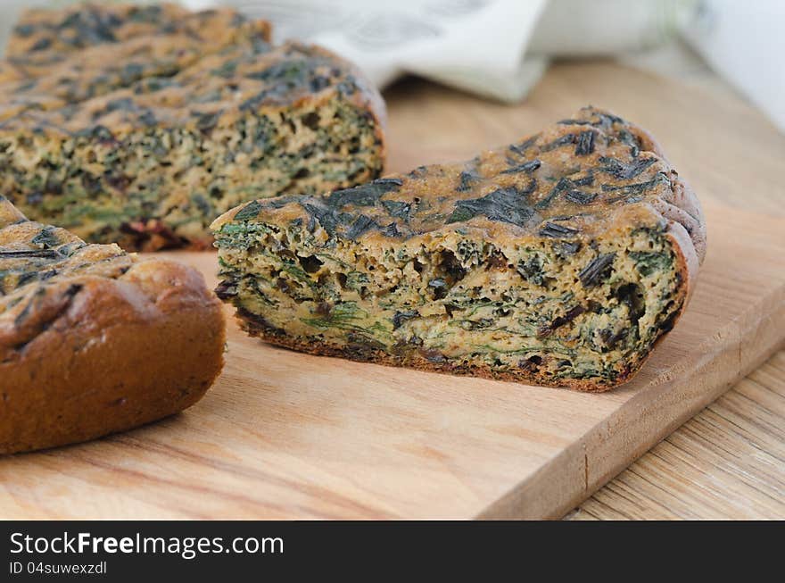 Piece of cake with fresh herbs and spinach on a wooden board closeup. Piece of cake with fresh herbs and spinach on a wooden board closeup