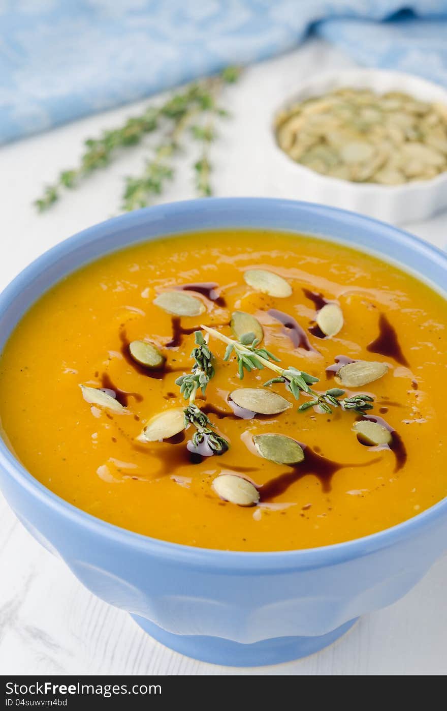 Pumpkin soup with pumpkin seeds and oil in a blue ceramic bowl, close-up. Pumpkin soup with pumpkin seeds and oil in a blue ceramic bowl, close-up