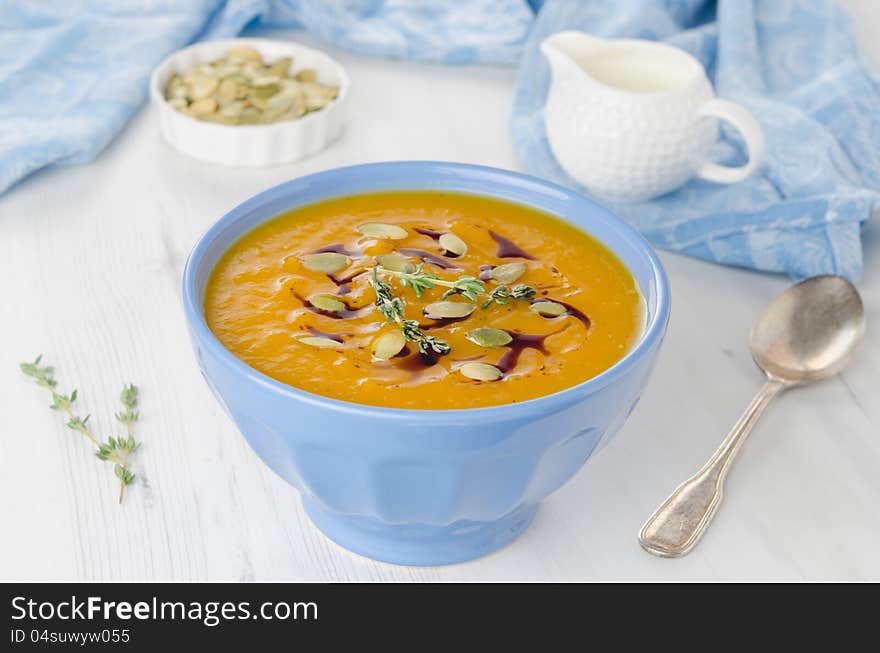 Pumpkin soup with pumpkin seeds and oil in a blue ceramic bowl, close-up horizontal. Pumpkin soup with pumpkin seeds and oil in a blue ceramic bowl, close-up horizontal