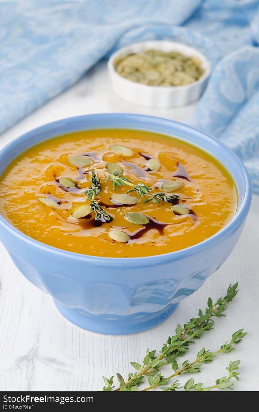 Pumpkin soup with pumpkin seeds and oil in a blue ceramic bowl, close-up. Pumpkin soup with pumpkin seeds and oil in a blue ceramic bowl, close-up