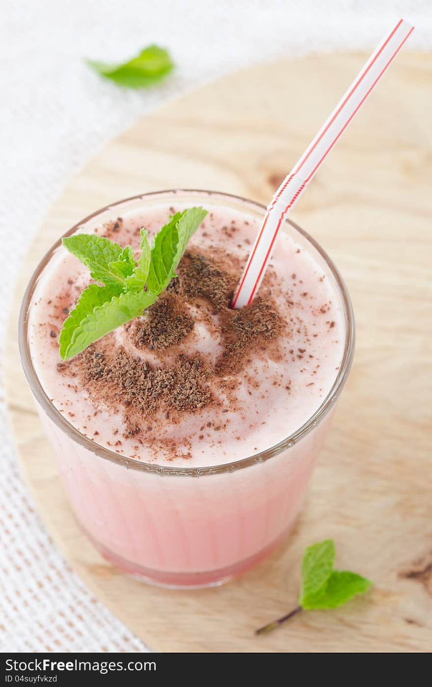 Milk cocktail with watermelon in a glass beaker, decorated with a sprig of mint and chocolate, close-up top. Milk cocktail with watermelon in a glass beaker, decorated with a sprig of mint and chocolate, close-up top