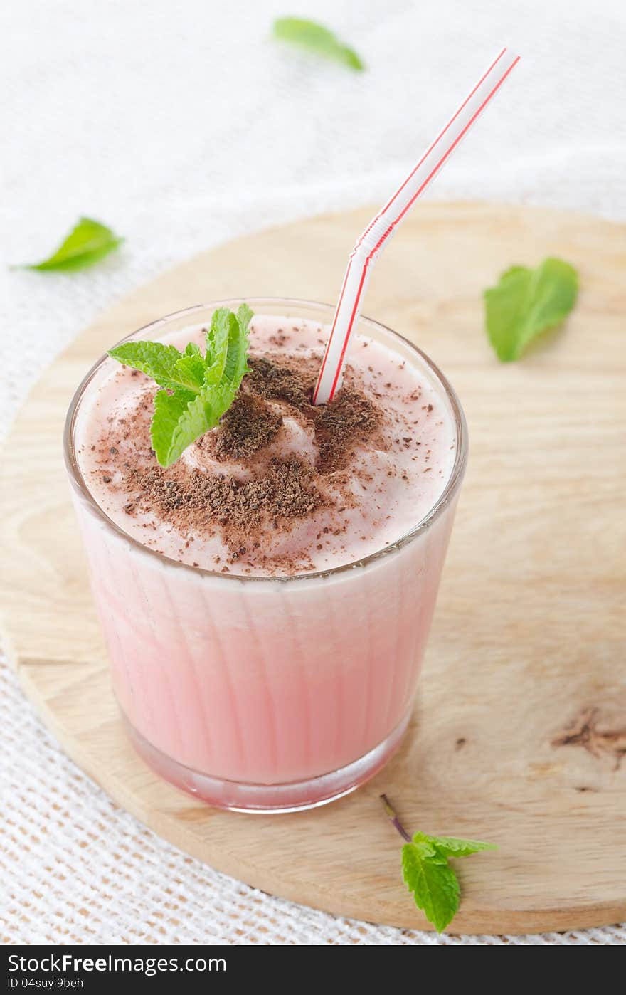 Milk cocktail with watermelon in a glass beaker, decorated with a sprig of mint and chocolate, close-up top. Milk cocktail with watermelon in a glass beaker, decorated with a sprig of mint and chocolate, close-up top