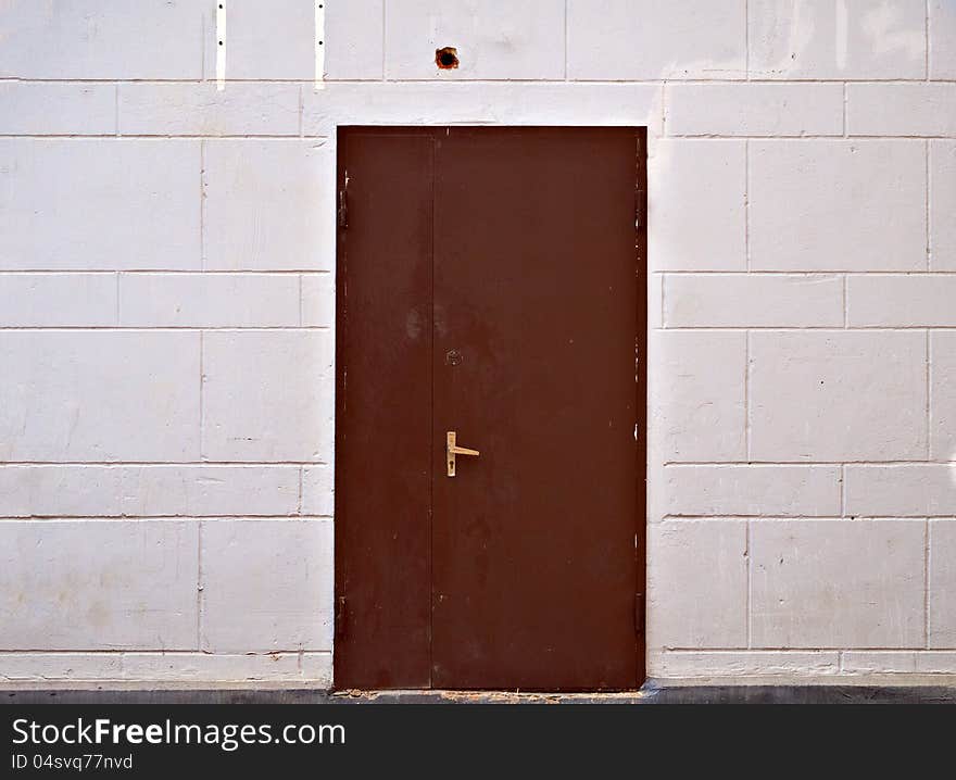 Rusty metal door in beige block wall