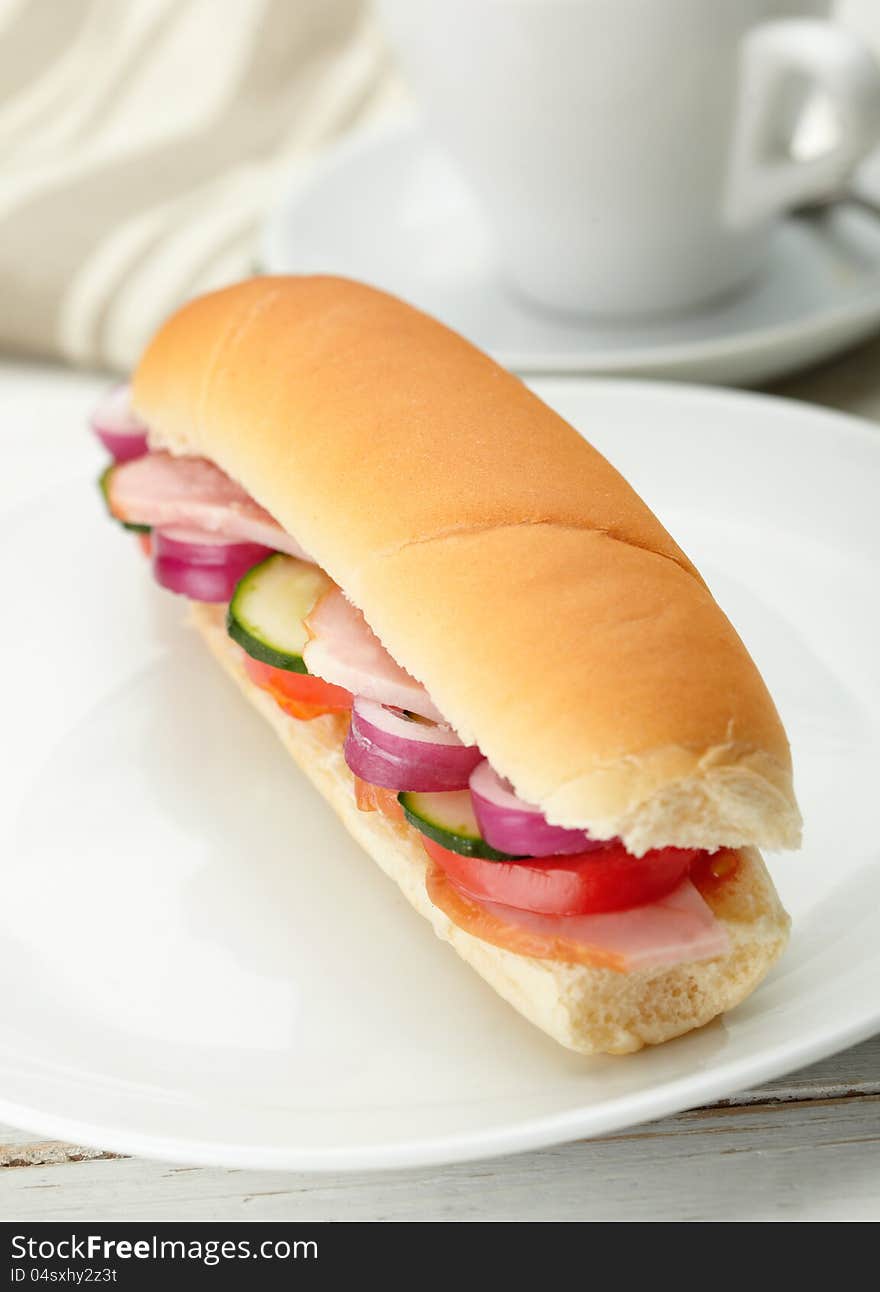 Small sandwich with deli meats and vegetables on a white plate