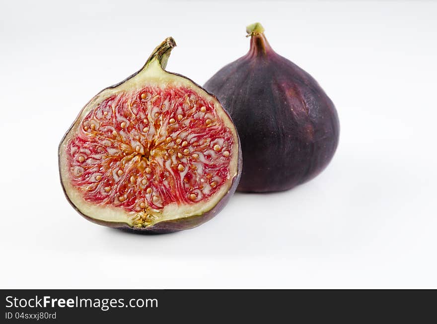 A shot of one fig and one half of fig on white , sharp details on seeds. A shot of one fig and one half of fig on white , sharp details on seeds