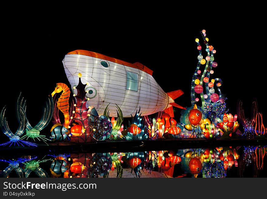 Colorful lanterns and their reflection in water, with colorful marine lives and submarine in shark shape.