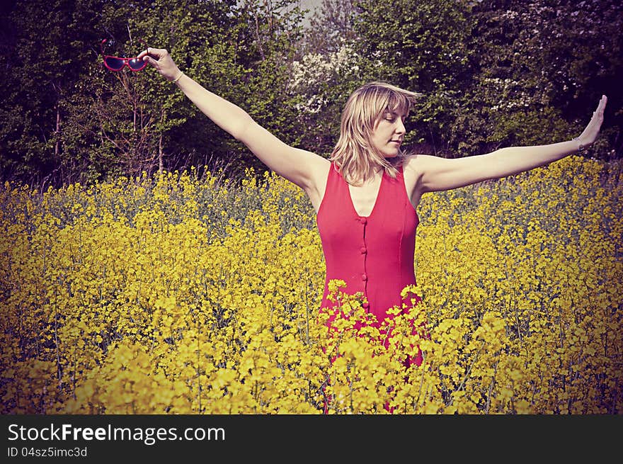 Girl in rapeseed field, dancing with joy.