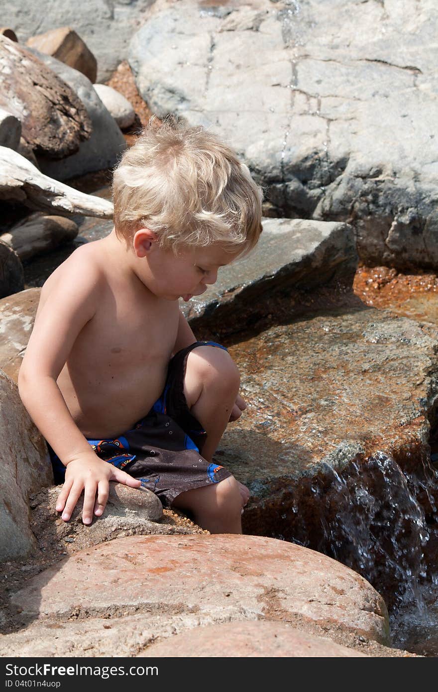 Small child wading and climbing in rocky stream. Small child wading and climbing in rocky stream.