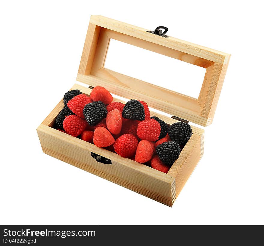 A wooden box with candies of black and red colors isolated on a white background. A wooden box with candies of black and red colors isolated on a white background