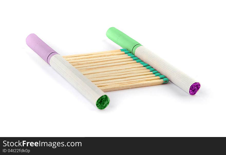 Two colored cigarettes with matches with green colored tips isolated on a white background. Two colored cigarettes with matches with green colored tips isolated on a white background