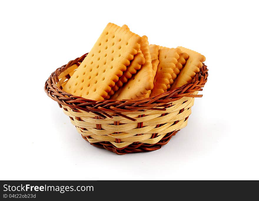 Pile of tea biscuits arranged in a straw basket isolated on a white background. Pile of tea biscuits arranged in a straw basket isolated on a white background