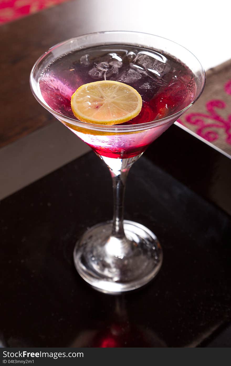 Brightly lighted pink drink in martini cocktails with lemon