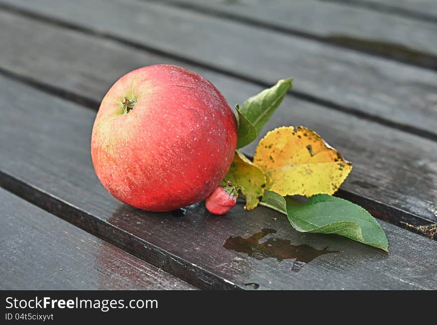 A red apple with leaves on a wooden table – HDR image. A red apple with leaves on a wooden table – HDR image