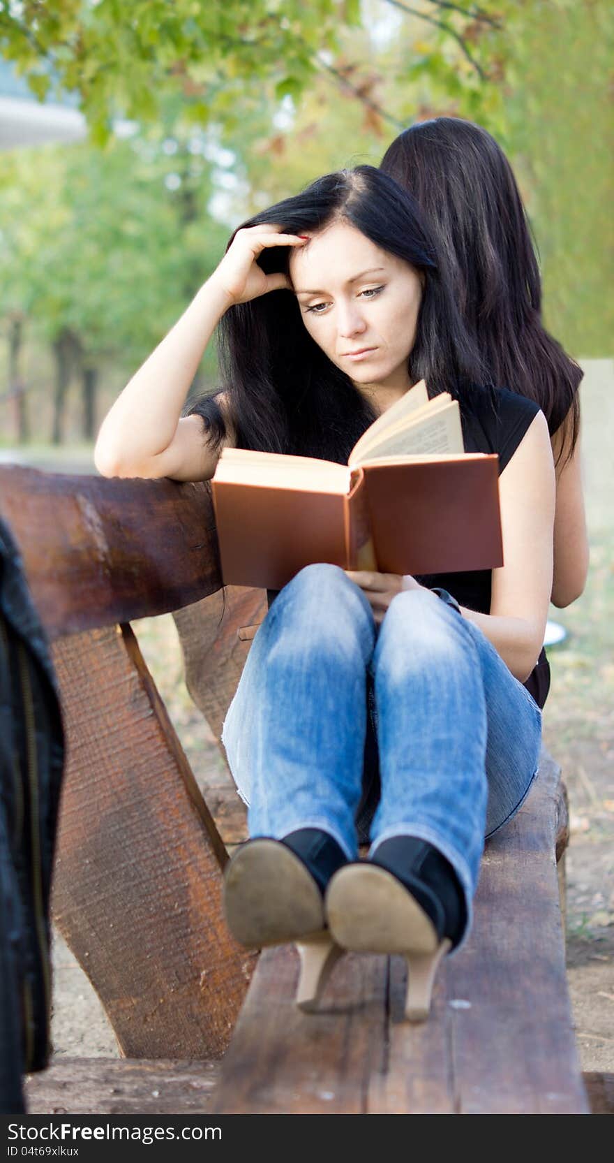 Girl Reading A Book On A Bench