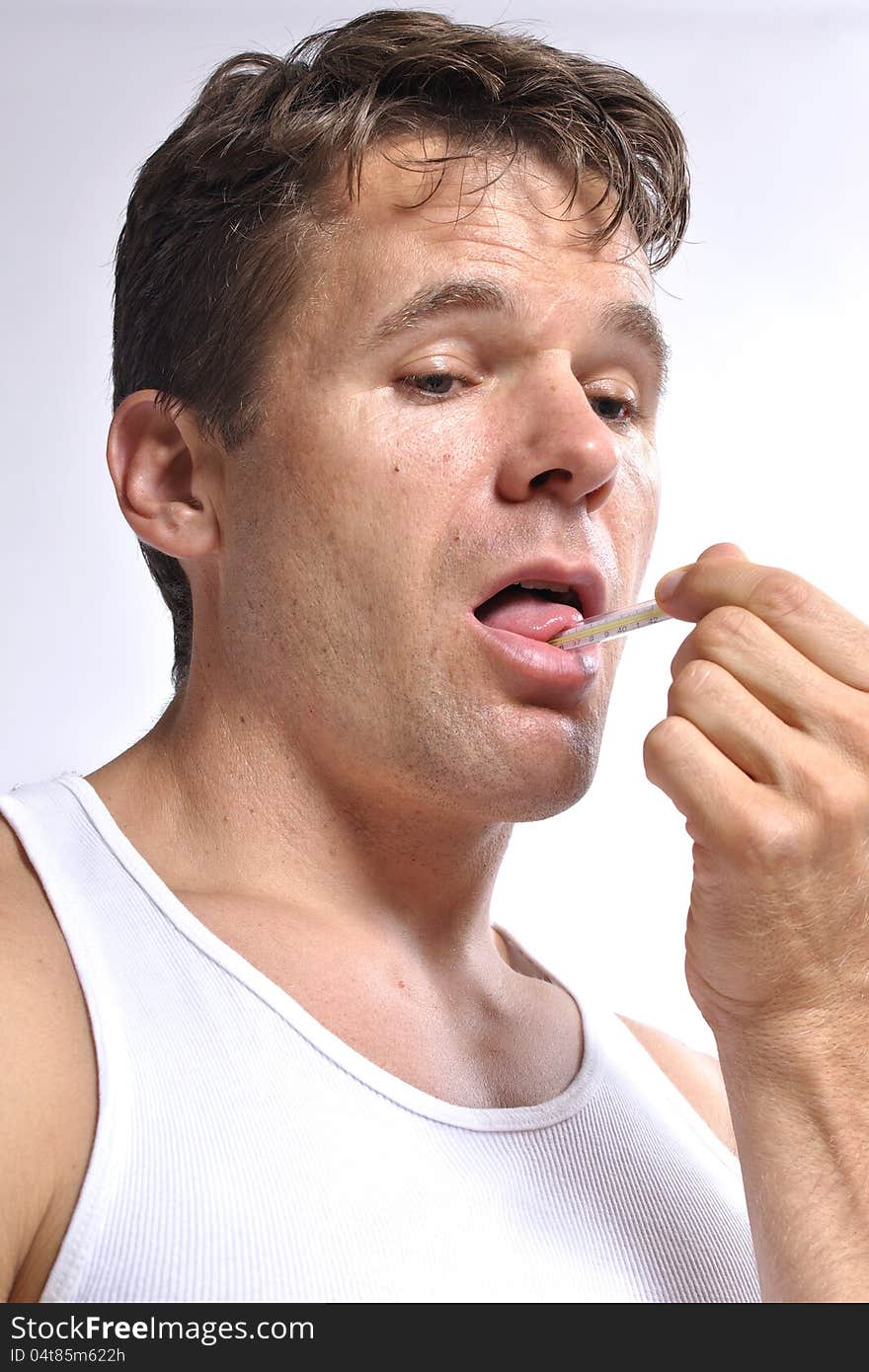 Sick man checks his temperature and holds thermometer under his own tongue