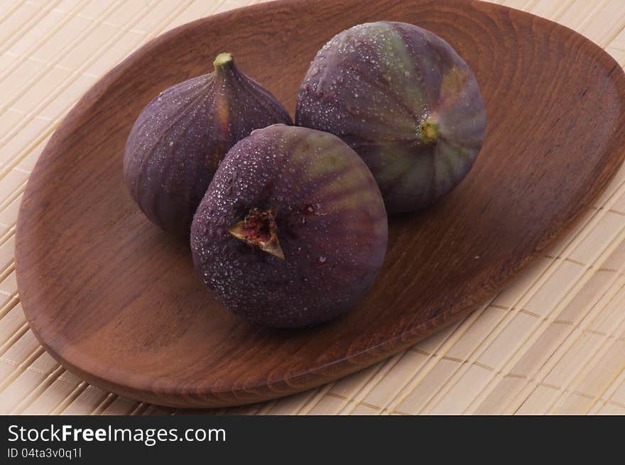 Three Perfect Ripe Figs Full Body with Droplets on Wooden Plate. Three Perfect Ripe Figs Full Body with Droplets on Wooden Plate