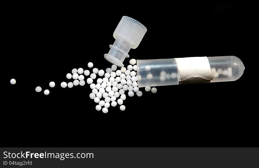 Homeopathic pills with tube isolated on black