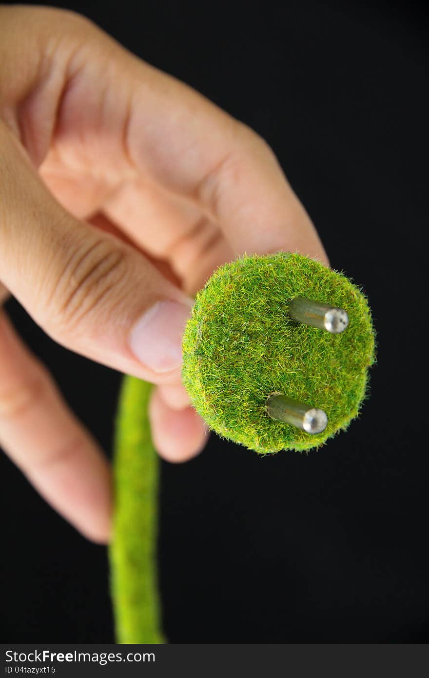 Hand holding green electric plug