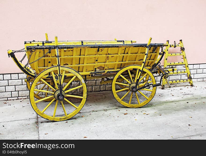 Old yellow wooden wagon standing in front of a wall of rose. Old yellow wooden wagon standing in front of a wall of rose