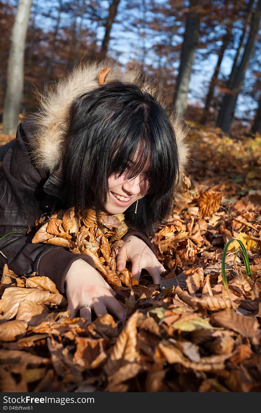 Girl playing with fallen autumn leaves in the forest. Girl playing with fallen autumn leaves in the forest