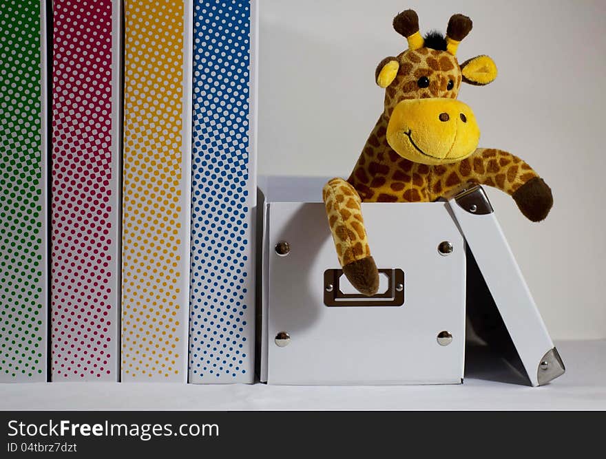 Plush giraffe sits smiling in a drop box. Plush giraffe sits smiling in a drop box.