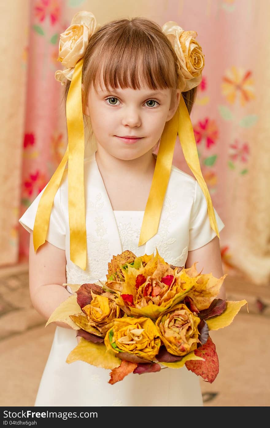 The little girl looks at the bouquet of autumn leaves. The little girl looks at the bouquet of autumn leaves