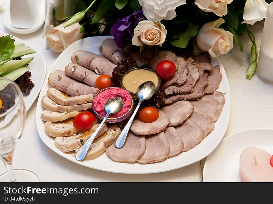 Sliced meat with mustard, horseradish and tomatos on a plate