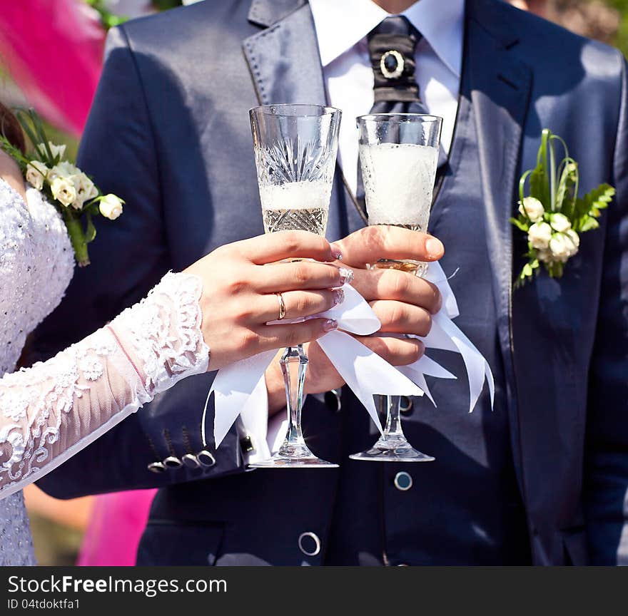 Glasses with champagne in hands newlyweds