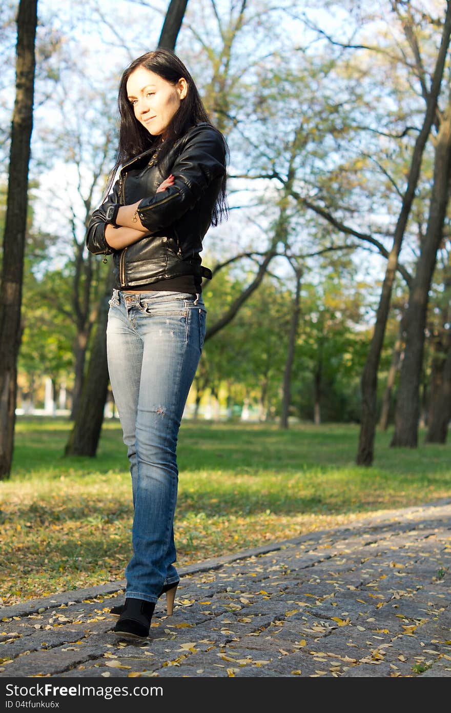 Low angle view of a modern attractive trendy young woman standing on a paved walkway in the country. Low angle view of a modern attractive trendy young woman standing on a paved walkway in the country