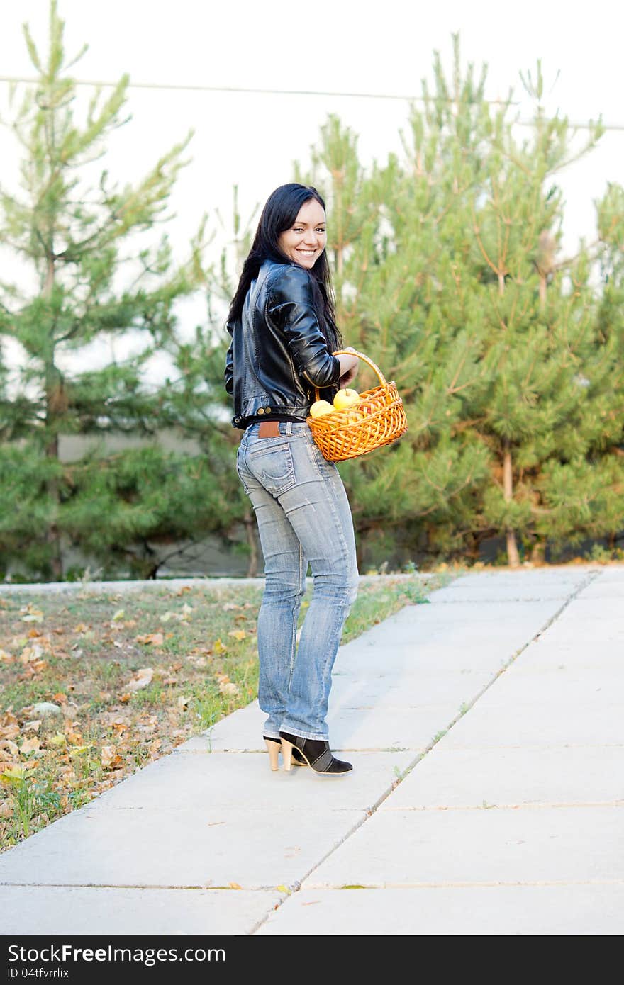 Attractive woman with basket of apples looking back over her shoulder as she walks along a pathway