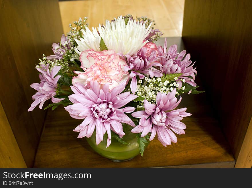 A jar of mixed flowers on shelf. A jar of mixed flowers on shelf