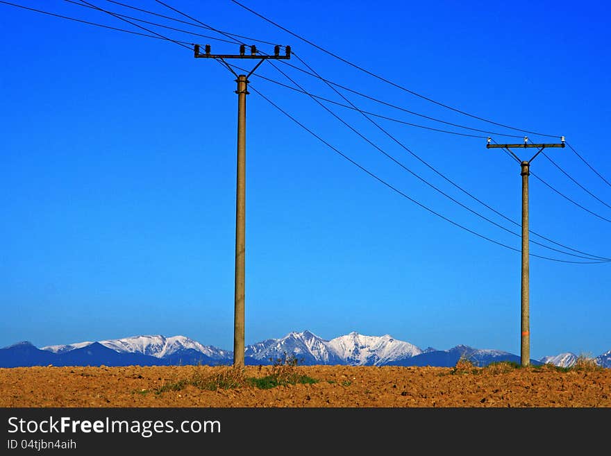 Electric power transmission on field in city Ruzomberok, Slovakia - High Tatras mountains in backround