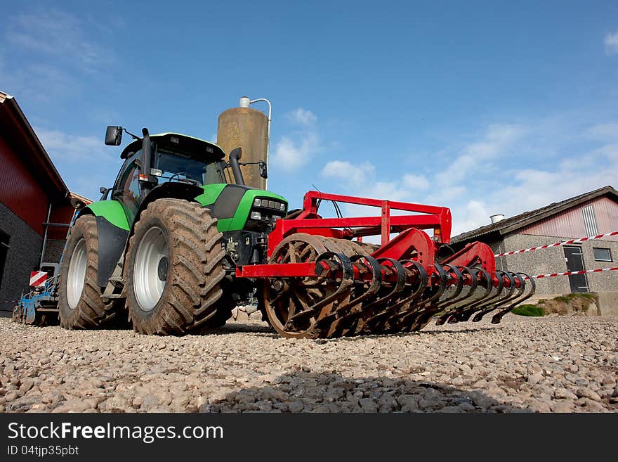 Modern tractor with a plow in a farm agriculture background image