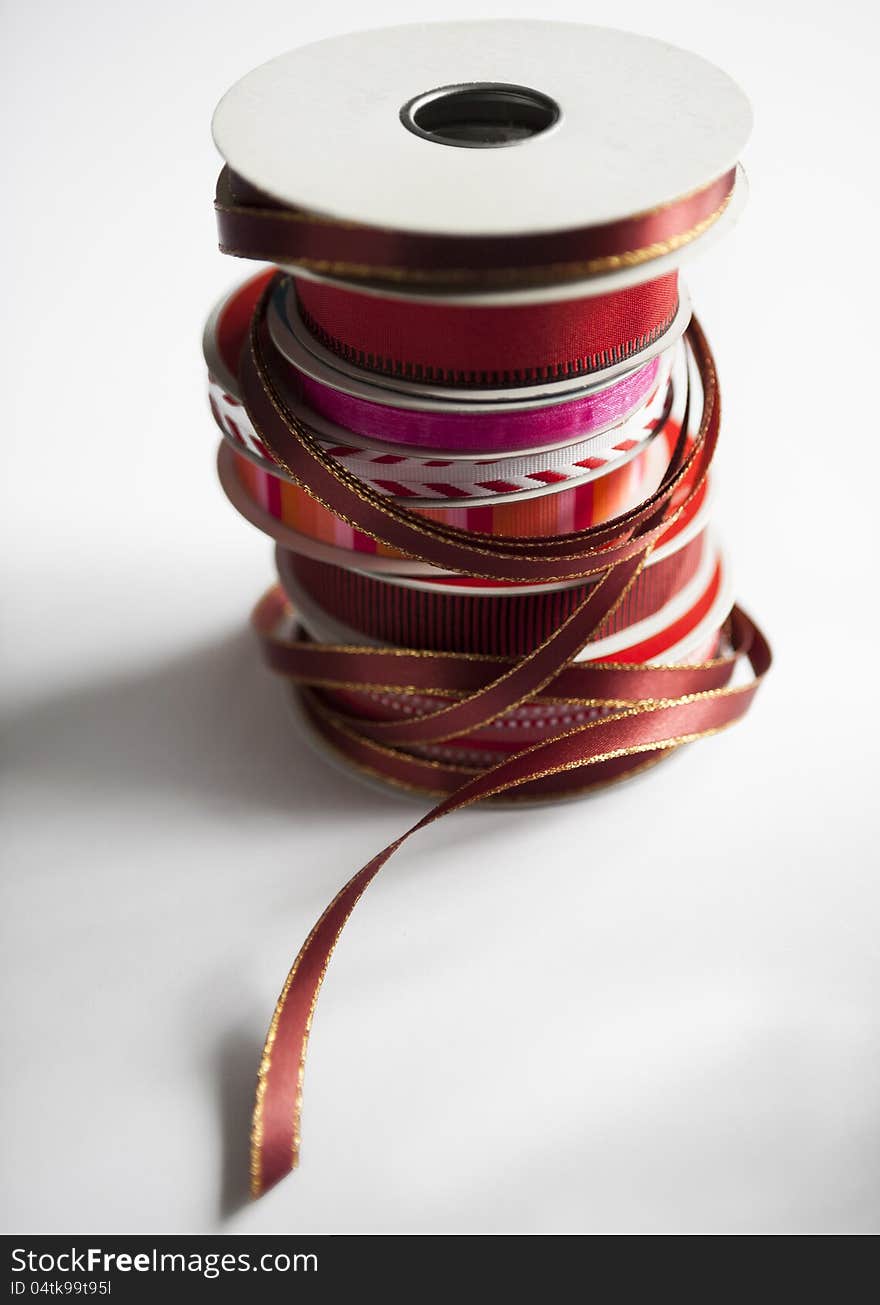 Stack of spools of holiday ribbons in red, white and gold on a white surface. selective focus. Stack of spools of holiday ribbons in red, white and gold on a white surface. selective focus